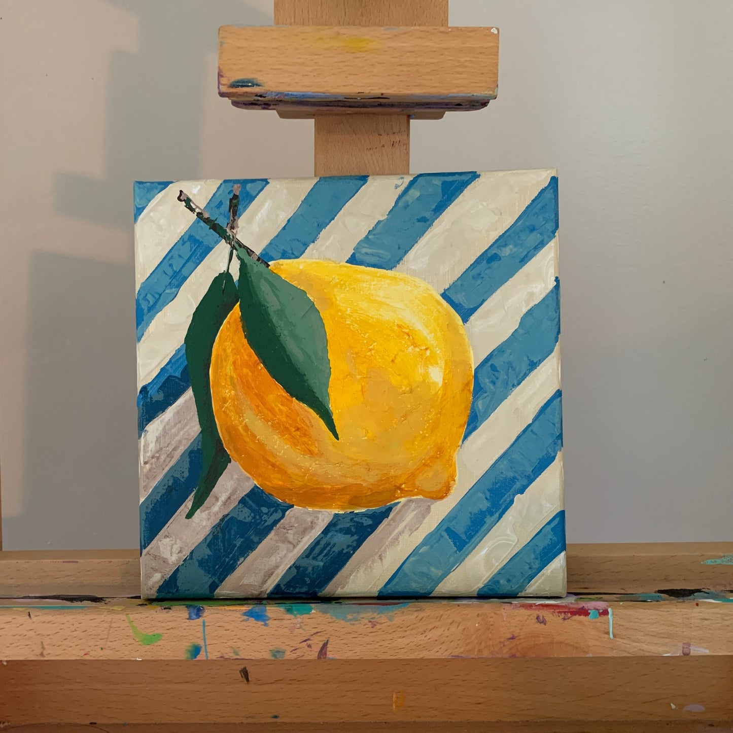 Canvas with a lemon painting on an easel against a white wall